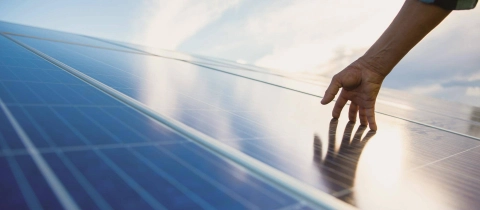 Eine Hand streicht zart über ein Solar-Panel.